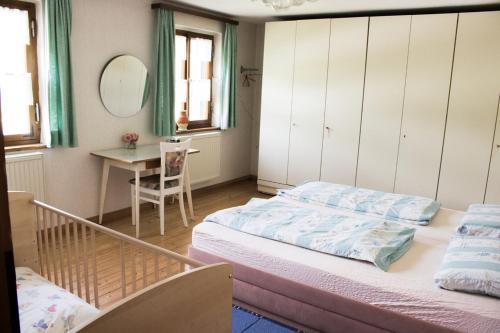 1 Schlafzimmer mit 2 Betten, einem Tisch und einem Spiegel in der Unterkunft Schwabenhof Ferienwohnung II in Leutershausen