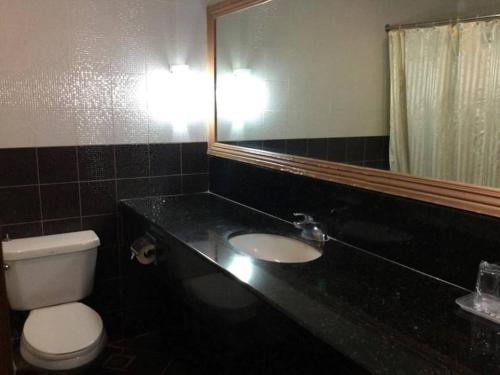 a bathroom with a toilet and a sink and a mirror at Dottie's Place Hotel & Restaurant in Butuan