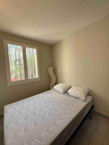 - une chambre avec un lit avec deux oreillers et une fenêtre dans l'établissement Appart Lagon Bleu Piscine Tennis, à Fréjus