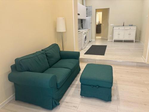 a living room with a green couch and a ottoman at Appartamento Albert in Livorno