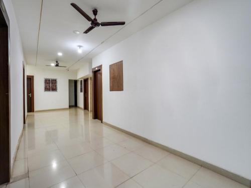 korytarzem z białymi ścianami i wentylatorem sufitowym w obiekcie OYO Tathastu Inn w mieście Raipur