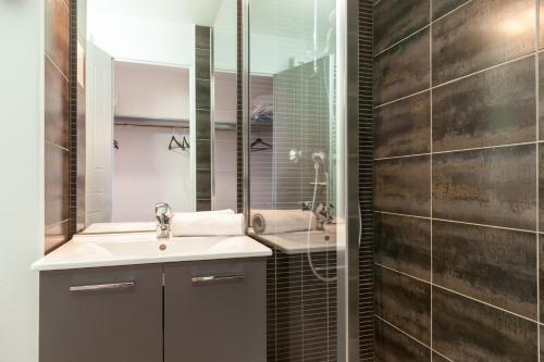 a bathroom with a sink and a mirror at The Originals City, Hôtel Le Louisiane, Belfort Sud (Inter-Hotel) in Andelnans