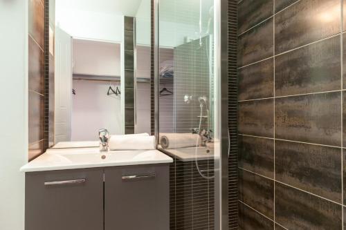 La salle de bains est pourvue d'un lavabo et d'un miroir. dans l'établissement The Originals City, Hôtel Le Louisiane, Belfort Sud (Inter-Hotel), à Andelnans