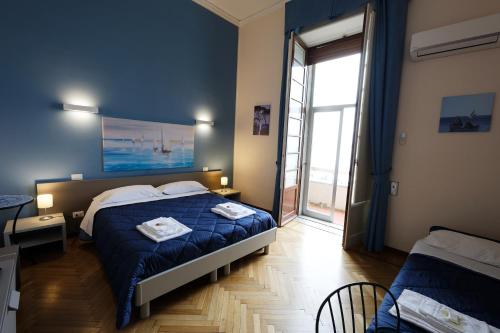 um quarto azul com uma cama e uma grande janela em Teatro sullo Stretto em Messina