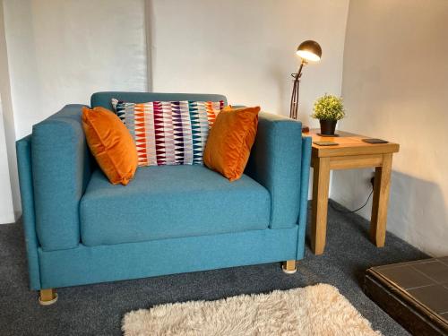 a blue chair with two orange pillows and a table at Leven's Rest - 2 Bed Maisonette in Backbarrow