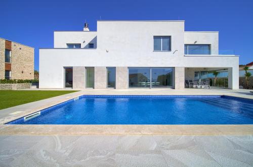 a white house with a swimming pool in front of it at Villa Sia in Krk