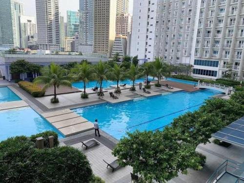 a man standing in front of a large pool with palm trees at 39th Flr Condo Unit with View in Manila
