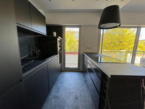 馬賽的住宿－Appartement T3 72 m²，一间厨房,配有黑色橱柜和大窗户