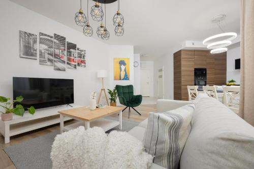 ein Wohnzimmer mit einem weißen Sofa und einem Tisch in der Unterkunft Złoty Potok Modern Family Apartment with Balconies & Parking Warsaw by Renters in Warschau
