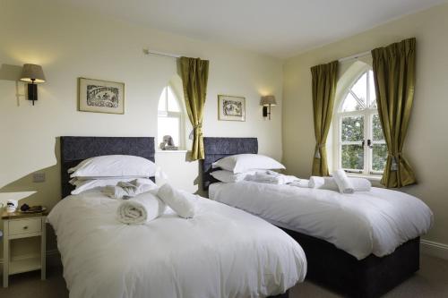 una camera con due letti con lenzuola bianche di Crows Hall a Colchester