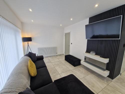 a living room with a couch and a flat screen tv at Modern Detached 3 bedroom home with off-road parking & bike store in Abercanaid