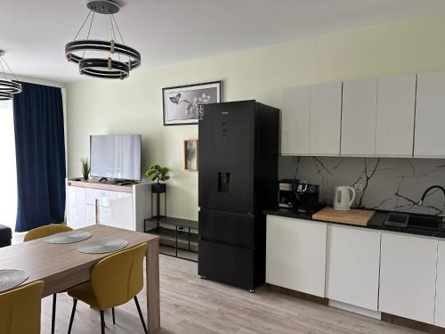 a kitchen with a table and a black refrigerator at Warmia Loft Apartament nad Iławką in Iława