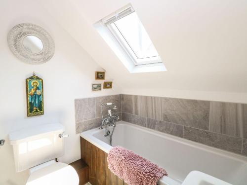 a bathroom with a toilet and a bath tub with a skylight at The Old Chapel in Bawdeswell