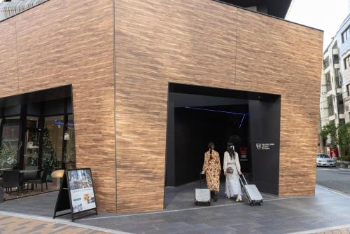 two people walking into a building with luggage at The Royal Park Canvas - Kobe Sannomiya in Kobe
