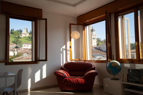 una sala de estar con una silla frente a las ventanas en Il Centrale, en Conegliano