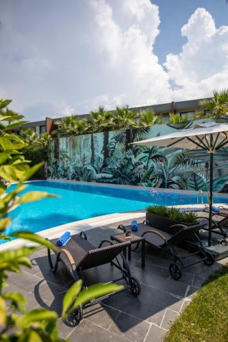 a pool with chairs and umbrellas next to a building at DoubleTree By Hilton Izmir Airport in Izmir