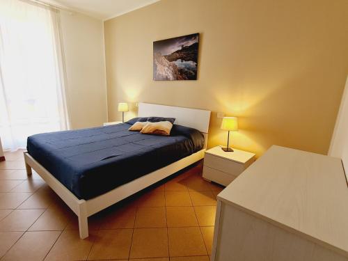 1 dormitorio con 1 cama con sábanas azules y 2 lámparas en Villaggio Mietta, en Castiglioncello