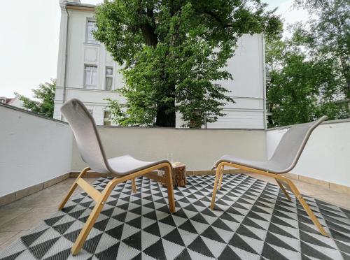 2 Stühle auf einem Balkon mit schwarzweißem Boden in der Unterkunft VIU Apartament Jadwigi V in Sopot