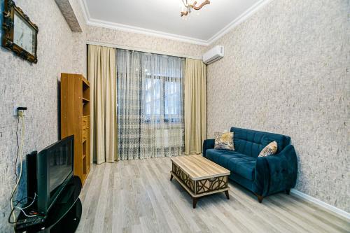 Deluxe Apartment 128/34 في باكو: غرفة معيشة مع أريكة زرقاء وتلفزيون