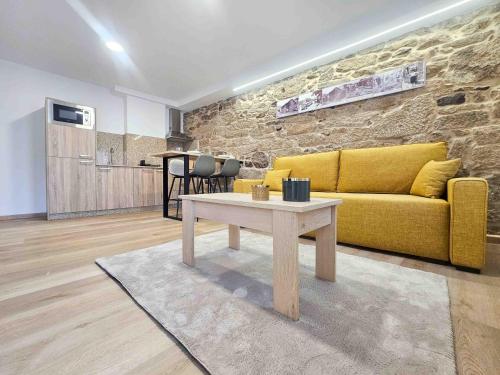 a living room with a yellow couch and a table at A Quinta de Cea - Apartamentos in Cea