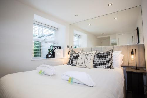 a white bedroom with a large white bed with pillows at Roker Sea Front Entire Modern One Bed Apartment in Sunderland