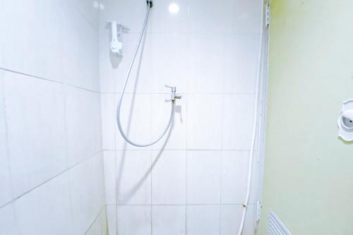 een douche met een slang in een witte badkamer bij 4N Residence RedPartner in Jakarta