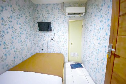 een slaapkamer met een bed en een tv aan de muur bij 4N Residence RedPartner in Jakarta