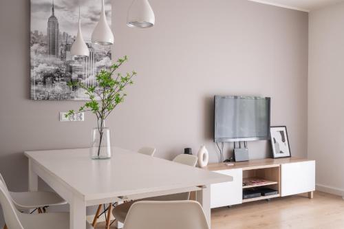 biała jadalnia z białym stołem i telewizorem w obiekcie RentPlanet - Apartament Partynice we Wrocławiu