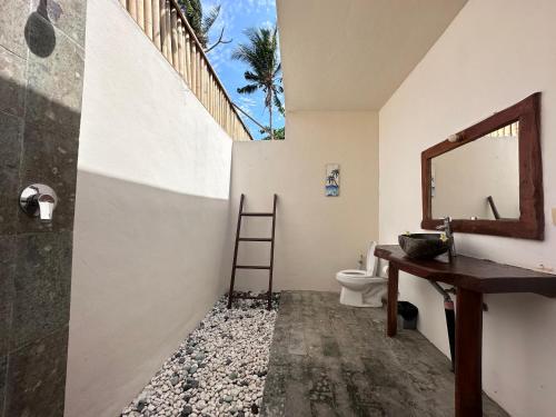 uma casa de banho com um WC, um lavatório e um espelho. em Pebble & Fins Bali Dive Resort em Tulamben