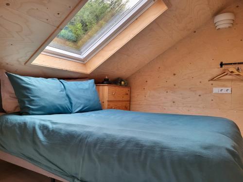 een bed in een kleine kamer met een raam bij Het Huisje comfortabel, luxe & sfeervol nabij het strand in Biggekerke