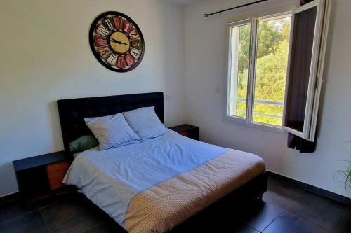 een slaapkamer met een bed en een klok aan de muur bij Appartement moderne*vue mer*accès plage in Solaro
