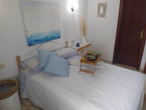 a bedroom with a white bed with a table on it at Amplio apartamento Blanes in Blanes