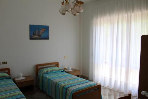 a bedroom with two beds and a window with curtains at B&B Il Melograno in Roccacasale