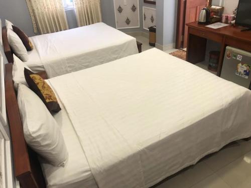 two beds in a hotel room with white sheets at THANH TAI HOTEl 1 in Ho Chi Minh City