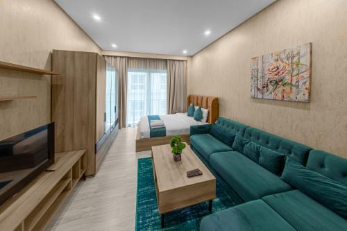 Vita Suites في المنامة: غرفة معيشة مع أريكة خضراء وسرير