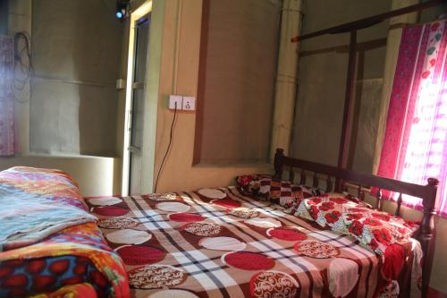 een bed met een dekbed en kussens erop bij Tharu COOP Homestay in Sauraha, Kathar :Chitwan in Sauraha