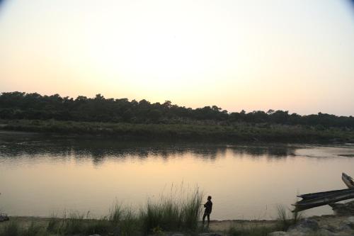 una persona in piedi accanto a un corpo idrico di Tharu COOP Homestay in Sauraha -Chitwan a Sauraha