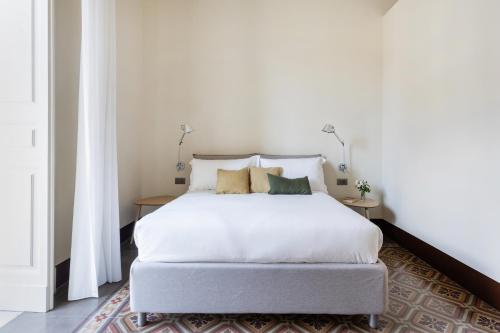 een slaapkamer met een wit bed en 2 tafels bij Palazzo Costarelli - Bed and Breakfast in Catania