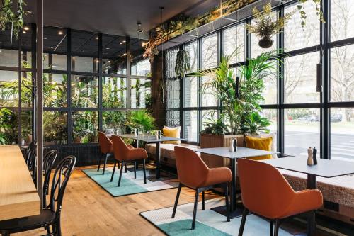 un restaurante con mesas, sillas y plantas en Hotel Schani Uno City, en Viena