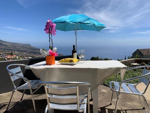 a table with a bottle of wine and a blue umbrella at Casa Jardim Panoramic View in Estreito da Calheta