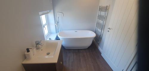 a bathroom with a white tub and a sink at Country Cottage Barn Conversion in Pollington