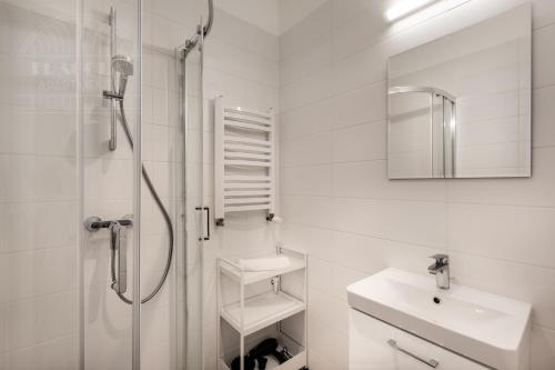 a white bathroom with a shower and a sink at Apartament Rynek Główny 7 in Krakow