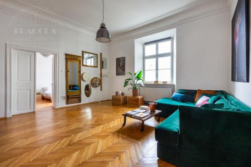 a living room with a green couch and wooden floors at Apartament Rynek Główny 7 in Krakow