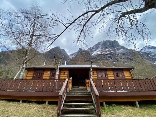 a wooden house with mountains in the background at Trollstigen Camping and Gjestegård in Åndalsnes