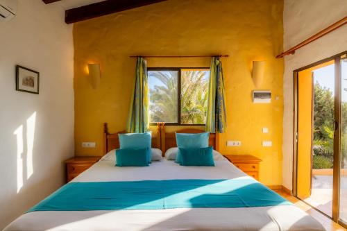 a bedroom with a large bed with blue pillows at Hotel Club Sunway Punta Prima in Es Pujols