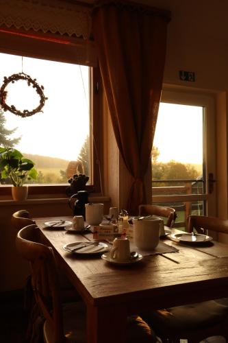 a table with cups and saucers on it with a window at Hotel Carolaruh in Bad Elster