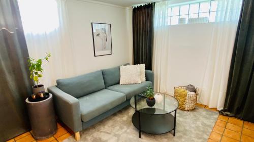 a living room with a blue couch and a glass table at Sundsvall By M - Basement Studio in Sundsvall