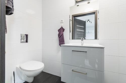 a white bathroom with a toilet and a sink at Villa del Sol in Sztutowo