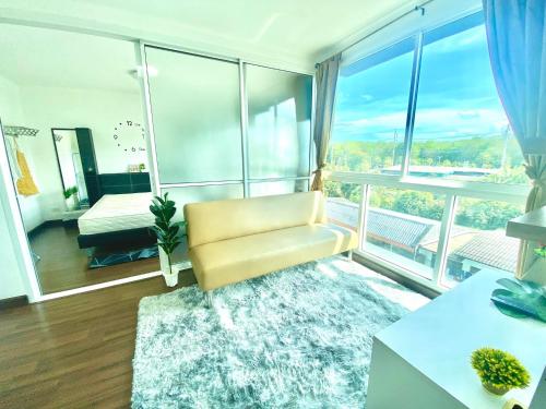a living room with a chair and a large window at The wide condo by Guide Sabai in Ban Tha Khreng