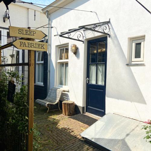 una casa blanca con una puerta azul y una señal en Mini appartement De Fabriek, en Nijmegen